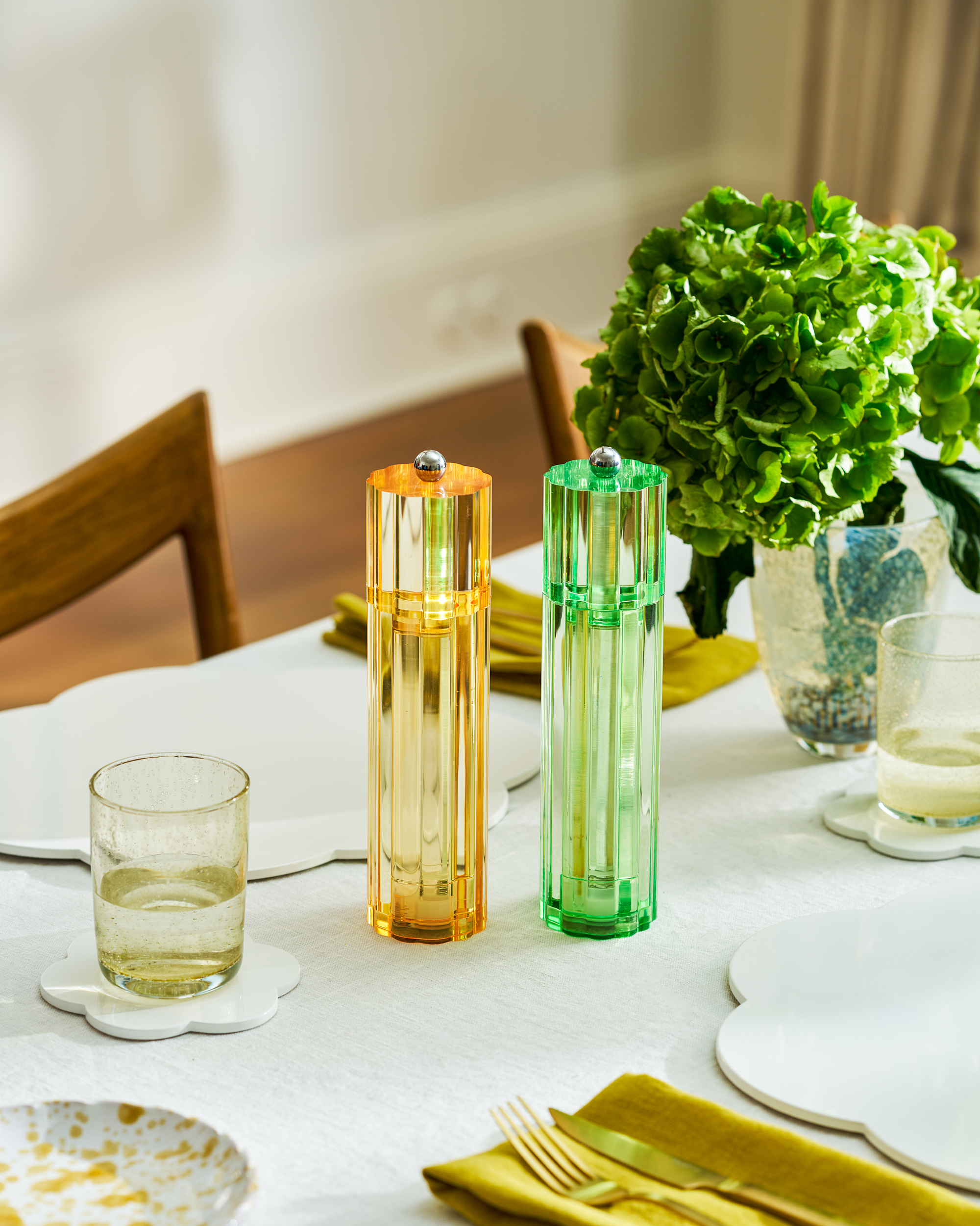 Image of an orange and green fluted salt and pepper mill sitting on a spring table top.