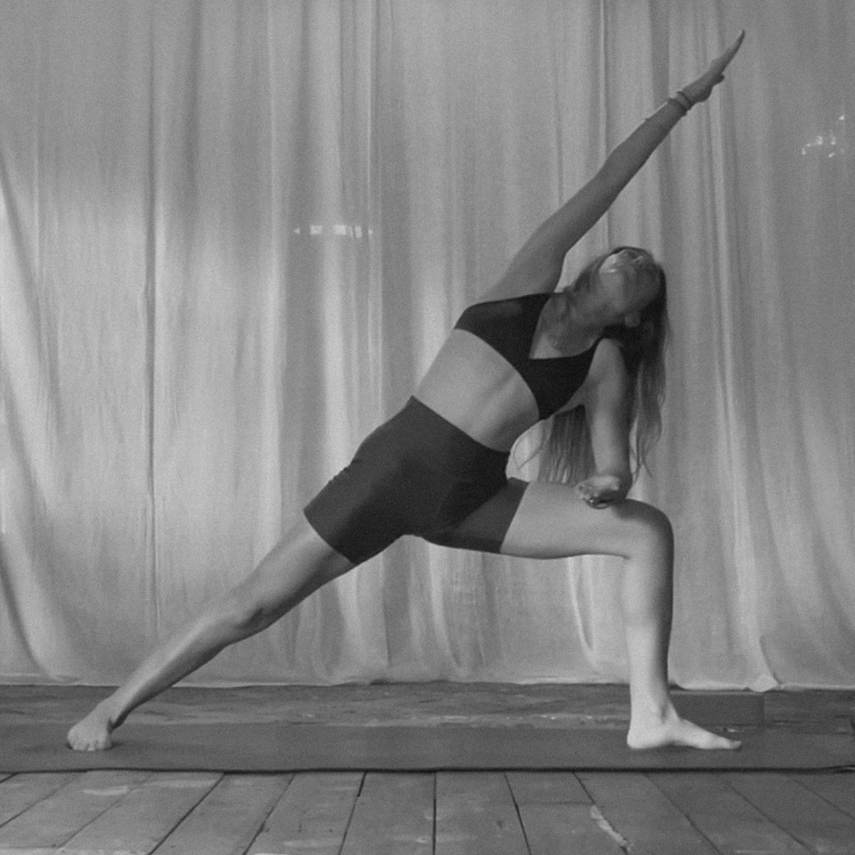 A woman doing yoga in a studio in shorts and a workout bra