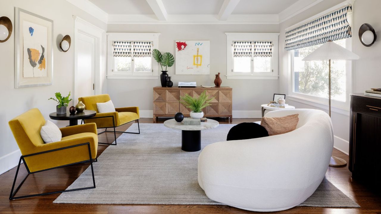 living room with white walls white sofa mustard accent chairs and gray rug