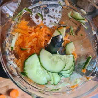 Close up of a Magic Bullet food processor bowl with carrots and cucumbers