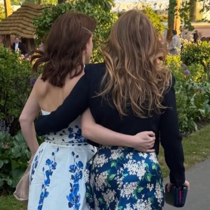 Princess Beatrice and Princess Eugenie walking with their arms around each other at the Chelsea Flower Show