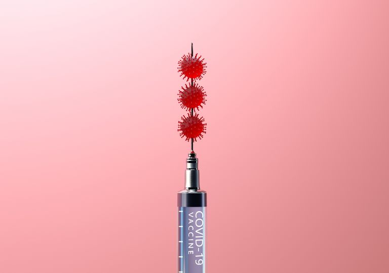 Digital generated image of Covid-19 cells on syringe needle against pink background, can the COVID vaccine delay your period?