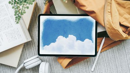 Drawing apps for iPad; a cloud and sky painted on a ipad, which sits on a coat on a table