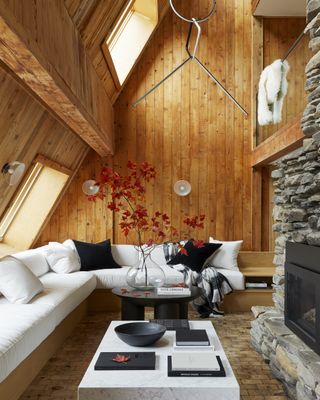 Living room with wood paneling, white sectional and fall foliage