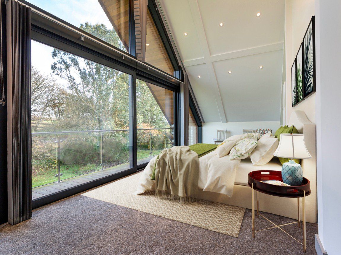 One of the bedrooms in side the property with large wall of window leading out to a balcony