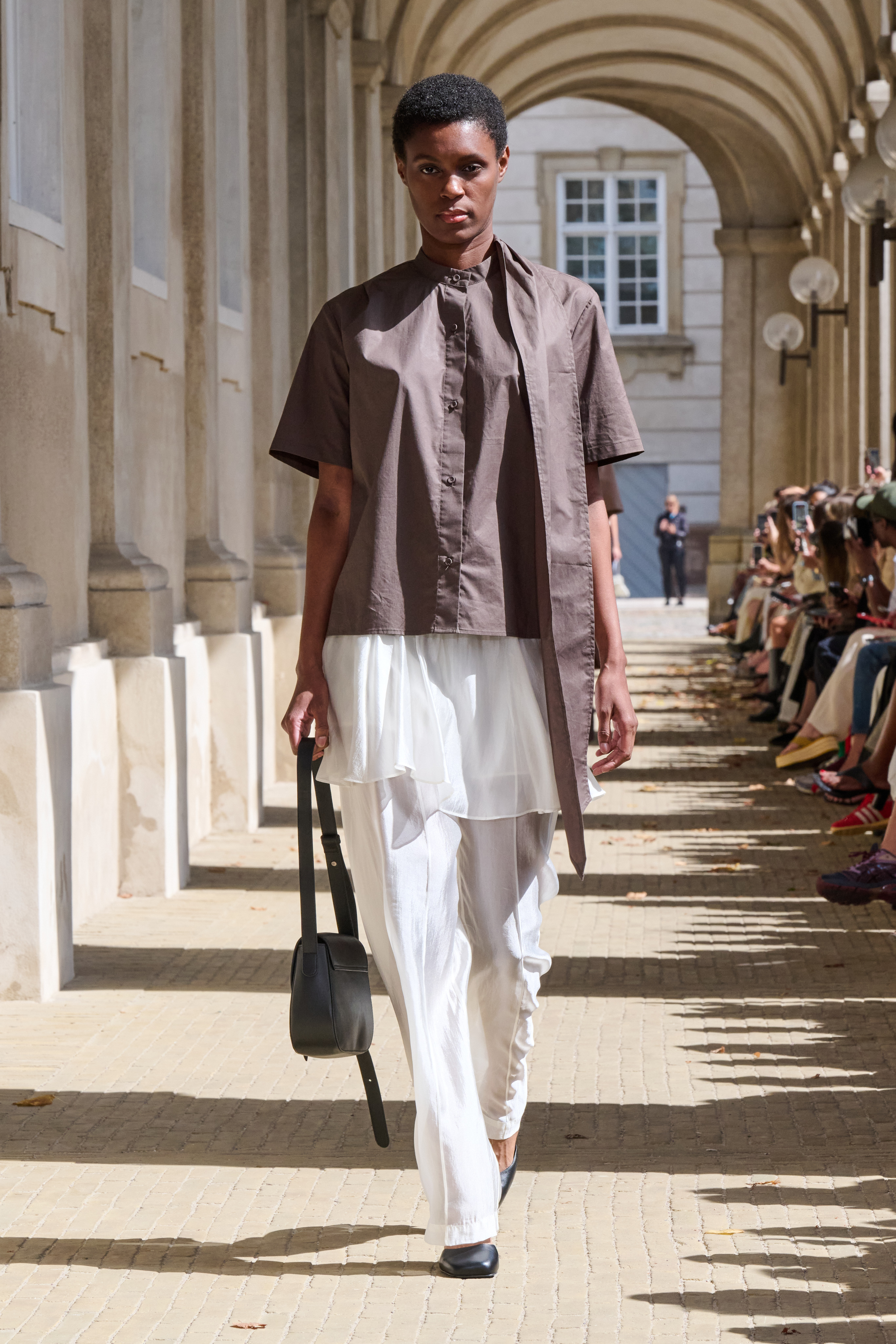 a model at The Garment wearing a tie neck top with a skirt over pants