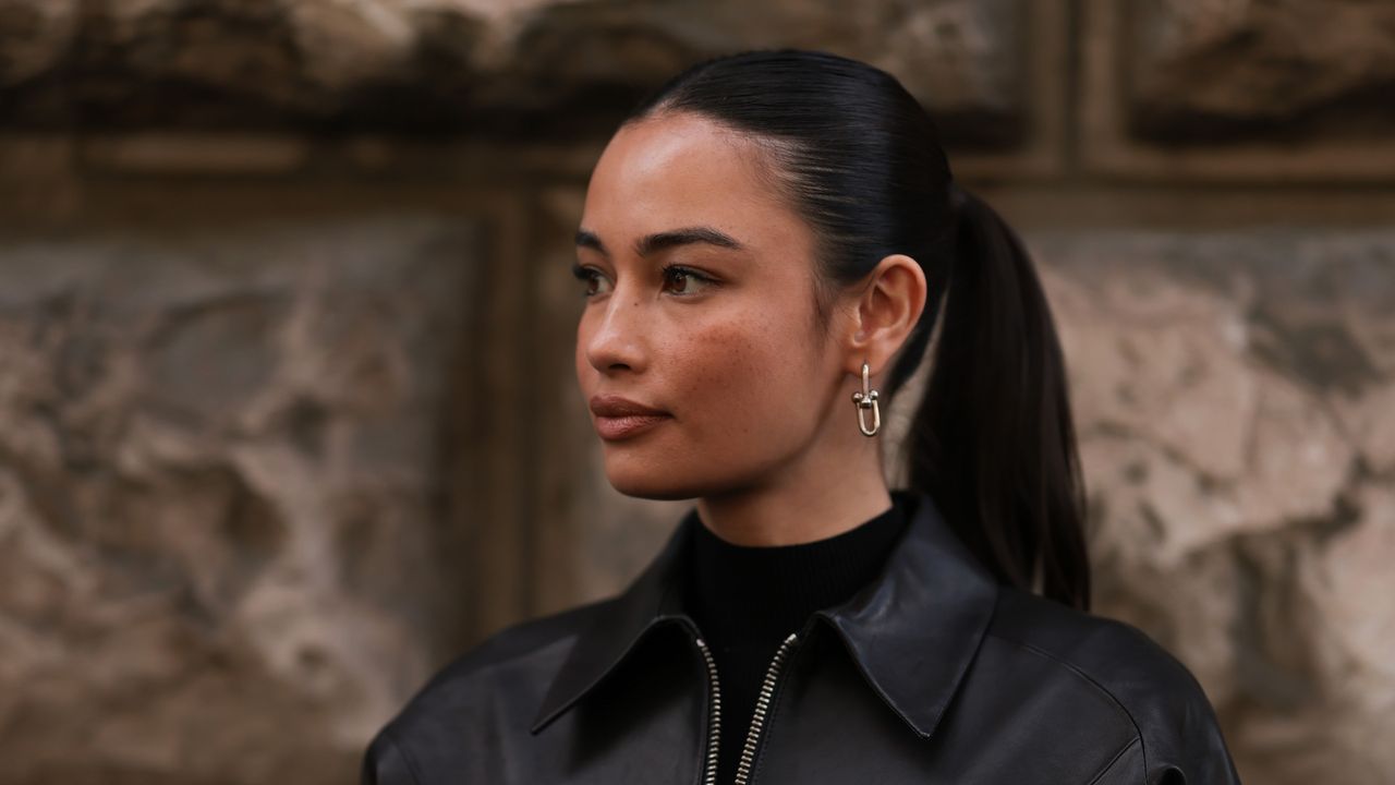 best foundations for oily skin - Kelsey Merritt wearing black leather jacket and silver earrings with sleek ponytail