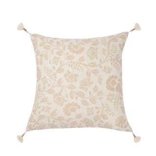 A white square throw pillow with a dark beige floral pattern and tassels on the corners