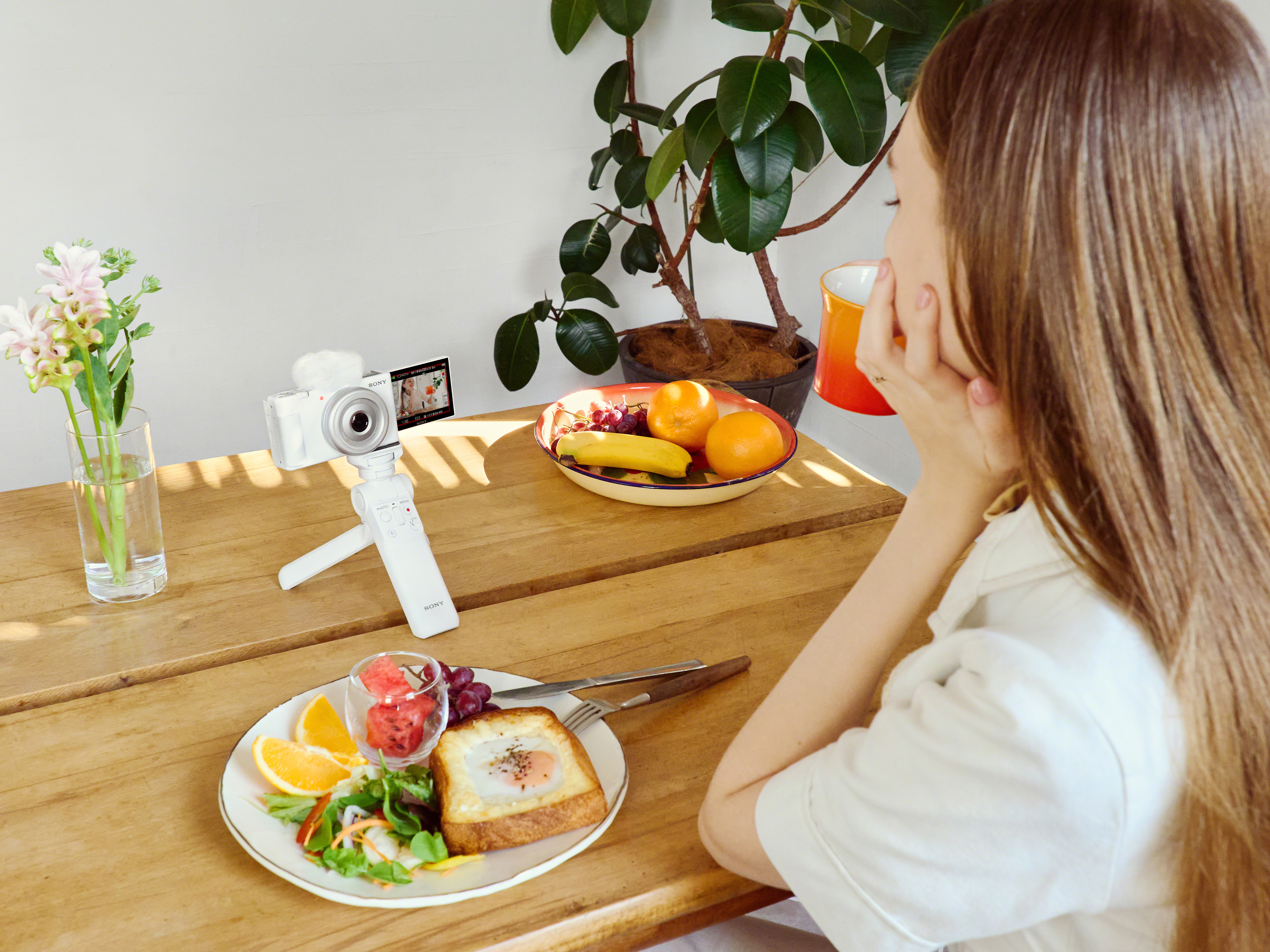 Person vlogging with Sony ZV-1F sitting on a table surrounded by food