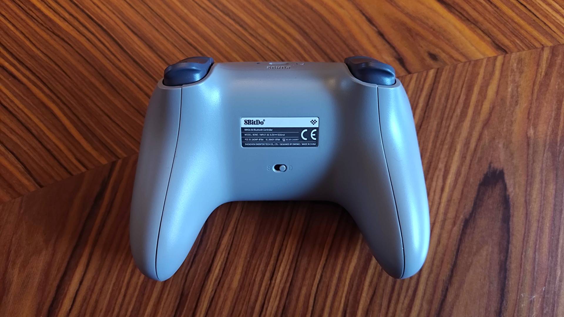 Back view of 8Bitdo N64 controller on woodgrain table.