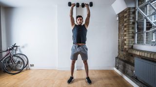 Man performs shoulder press exercise at home