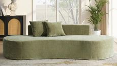 Image of a velvet, sage green curved sofa with two matching pillows on it.