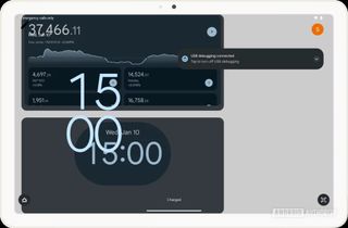 The Pixel Tablet showing a mashup of the lock screen with a clock and user icons, and widgets for another clock app and an app tracking stock prices.