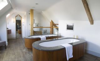 Bathroom in Calcot Manor, Gloucestershire, UK with two baths with marble surround and wooden paneling