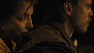 Jodie Comer sits behind Austin Butler as they ride into the night in The Bikeriders.