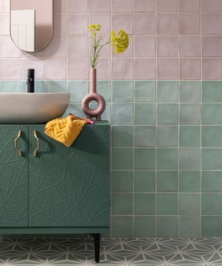 Small bathroom with green and pink wall tiles, a grey geo patterned floor and a green vanity unit
