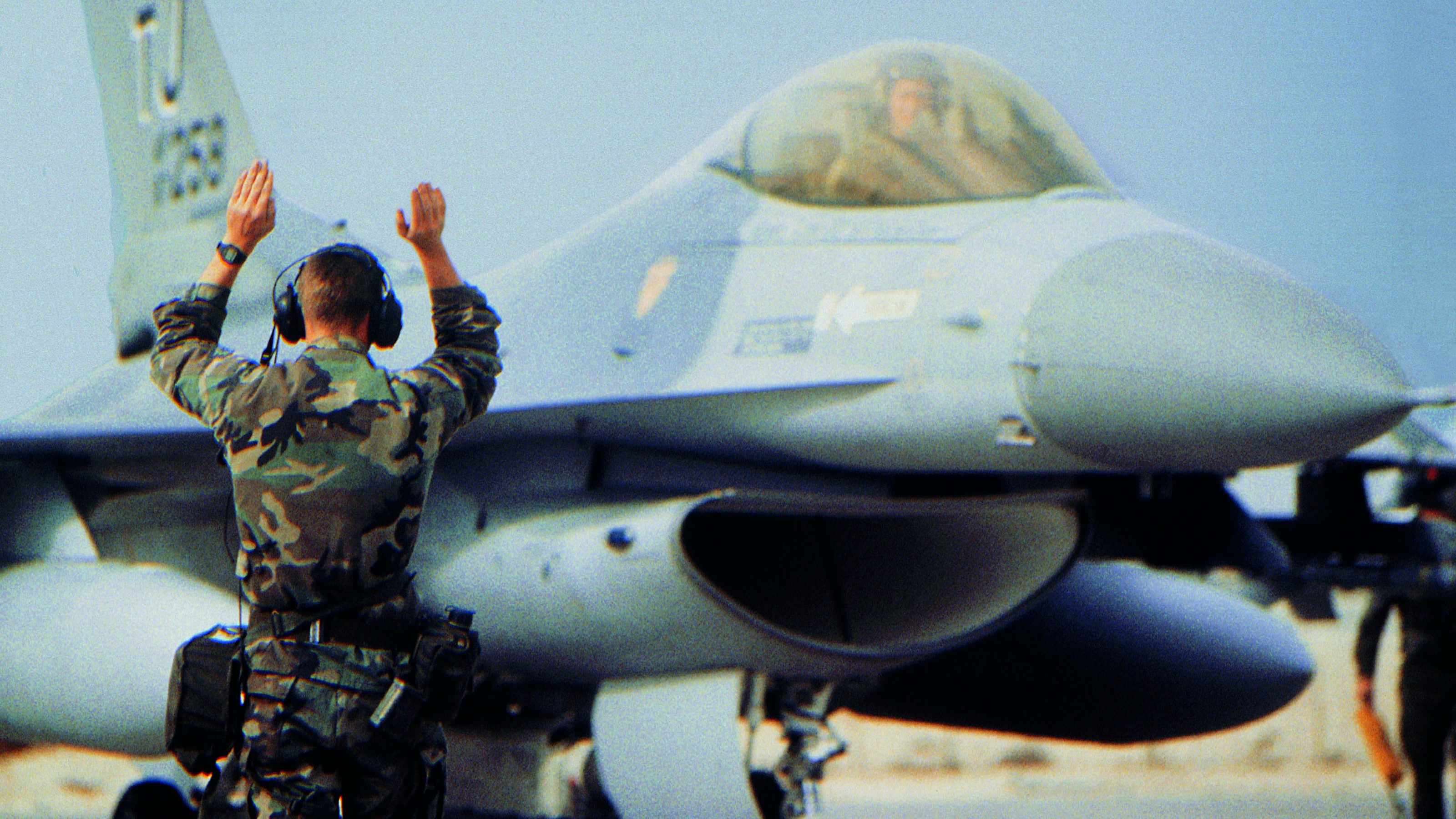 Ground crew signals to a military jet.