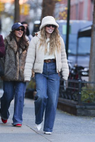 A photo of Sydney Sweeney pairing wide-leg jeans with pointy white ankle boots.