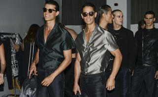 Two models wearing shiny shirts and dark glasses