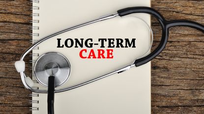The words long-term care on an open notebook with a stethoscope wrapped around them.