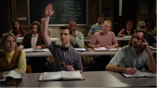 Sheldon Cooper (Iain Armitage) with his hand raised in a classroom in Young Sheldon