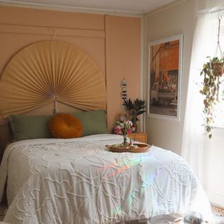 goldenhourabode boho bedroom with tan walls, white comforter, light coming in from the windows and plants