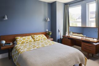 A bedroom with mid-century furniture and deep blue walls