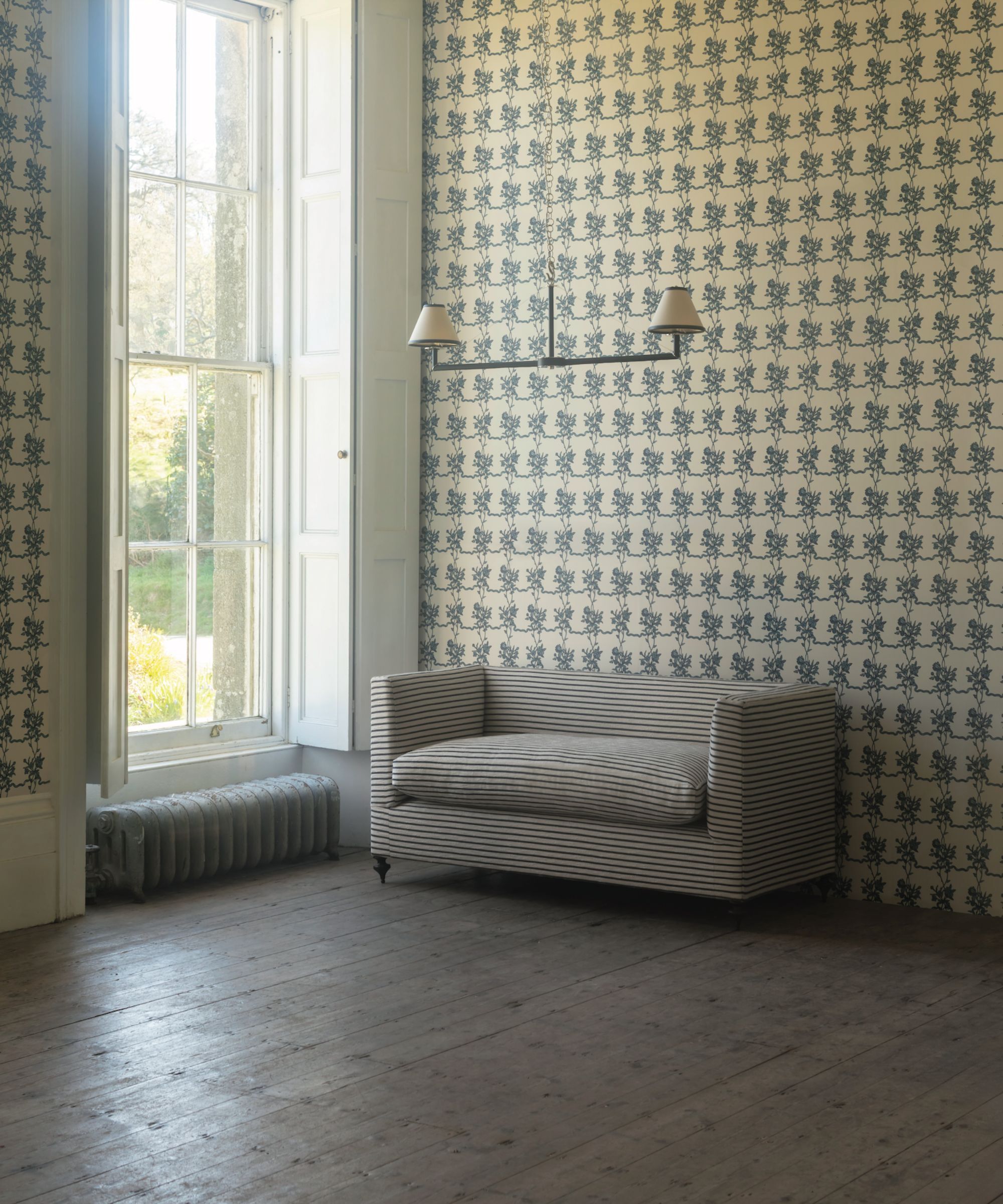 Floral wallpaper in a large room with a plain striped sofa