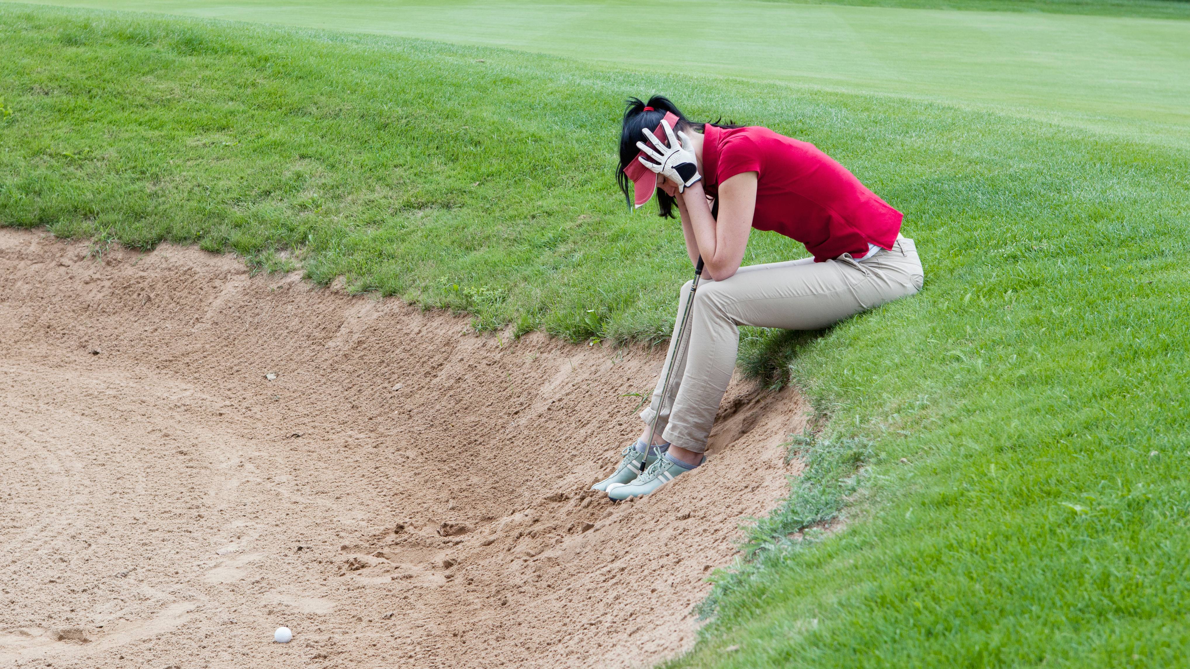Female golfer in despair in bunker