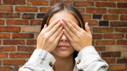 A young woman covers her eyes.