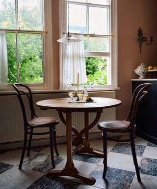 bistro table and chairs in a corner of a muted kitchen by devol with checkerboard marble floor