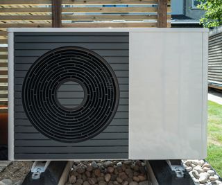 heat pump in garden with wooden slatted fence panel behind it