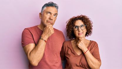 Studio portrait of puzzled middle age couple thinking about a question