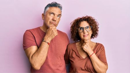 Studio portrait of puzzled middle age couple thinking about a question