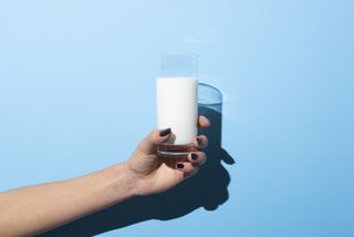 A woman's handing holding a glass of oat milk