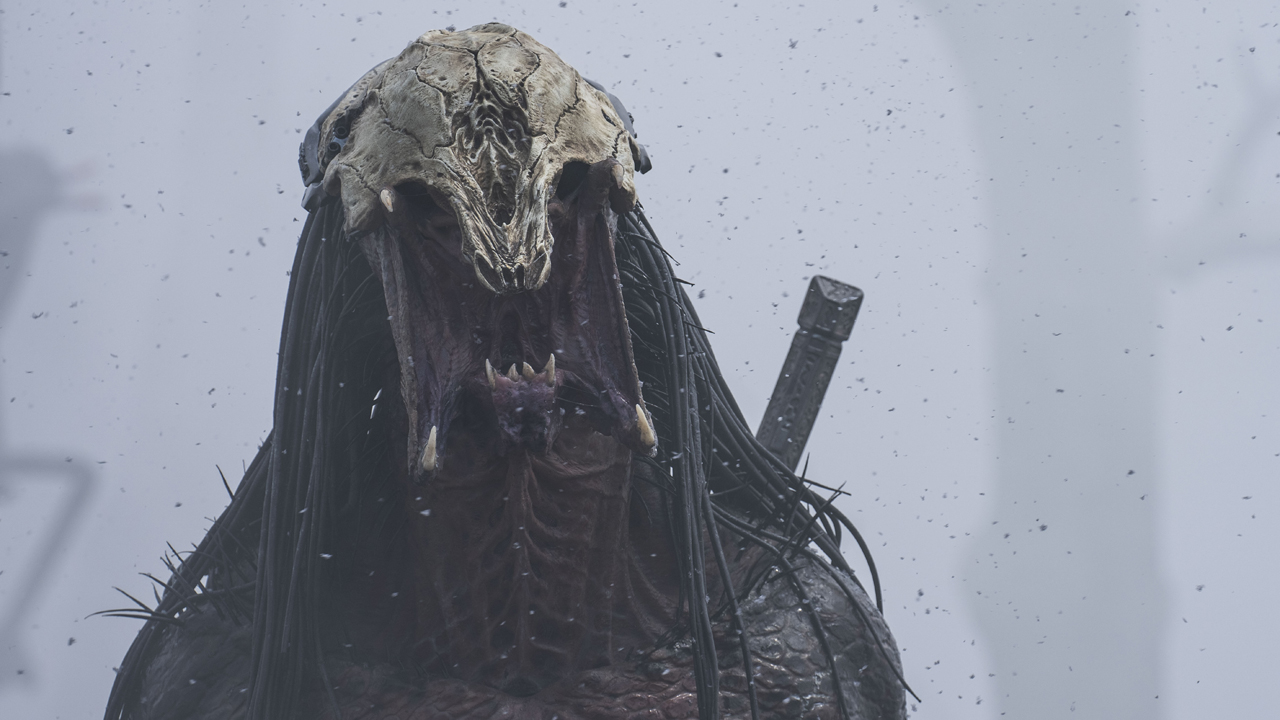 Хищник, с его шлем с черепом на голове ревет над бесплодным, наполненным дымом пейзажем в Prey