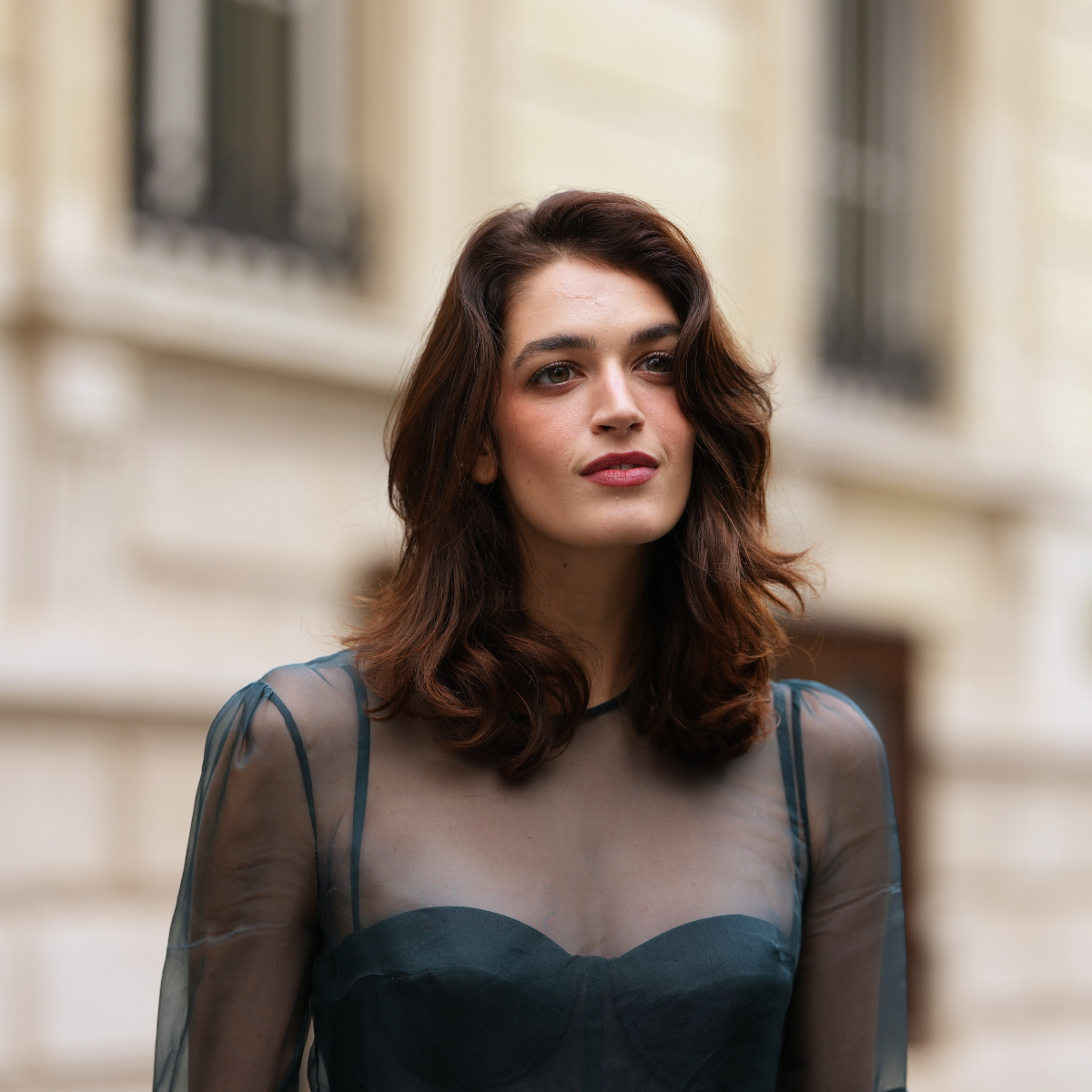 Makeup for hooded eyes Greta Ferro wears shoulder-length wavy dark brown hair with a side part, a sheer teal organza long-sleeve top layered over an opaque structured teal bustier with a sweetheart neckline, dramatic flared organza trumpet sleeves, a peplum-style waist composed of opaque and sheer organza panels, outside Zimmermann, during Paris Fashion Week - Womenswear Spring Summer 2026,