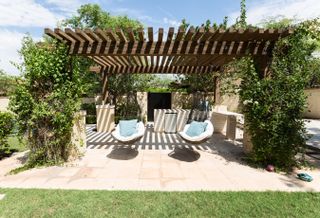 outdoor living area with pergola, hanging armchairs, outdoor kitchen