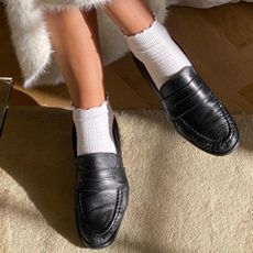 stylish swedish woman posing with ruffled ankle socks and black loafers