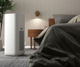 A dehumidifier by a bed with slate grey sheets