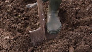 picture of person wearing wellies digging in garden