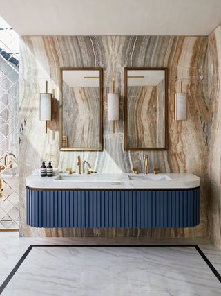Blue fluted double vanity in a marble bathroom