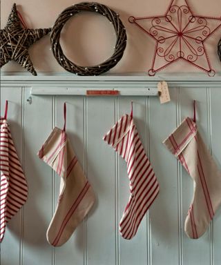 pastel blue tongue and groove panelled wall, handmade striped Christmas stockings, wicker wreaths, stars decorations