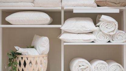 White shelving with white linens and pillows on them