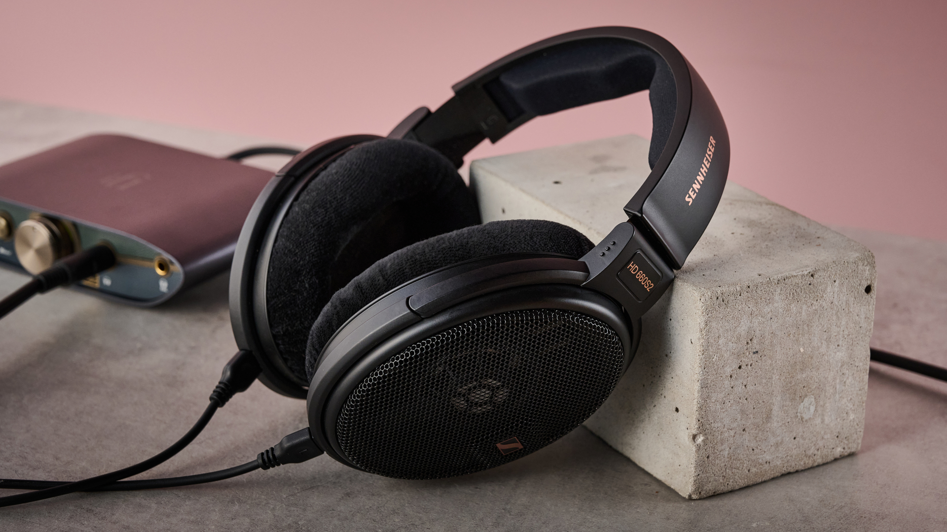 The Sennheiser HD 660S2 leaning against a concrete block in the foreground, with the iFi Zen DAC 3 in the background.