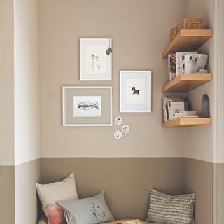 Three framed prints on wall next to shelves with books, on two tone sage green wall