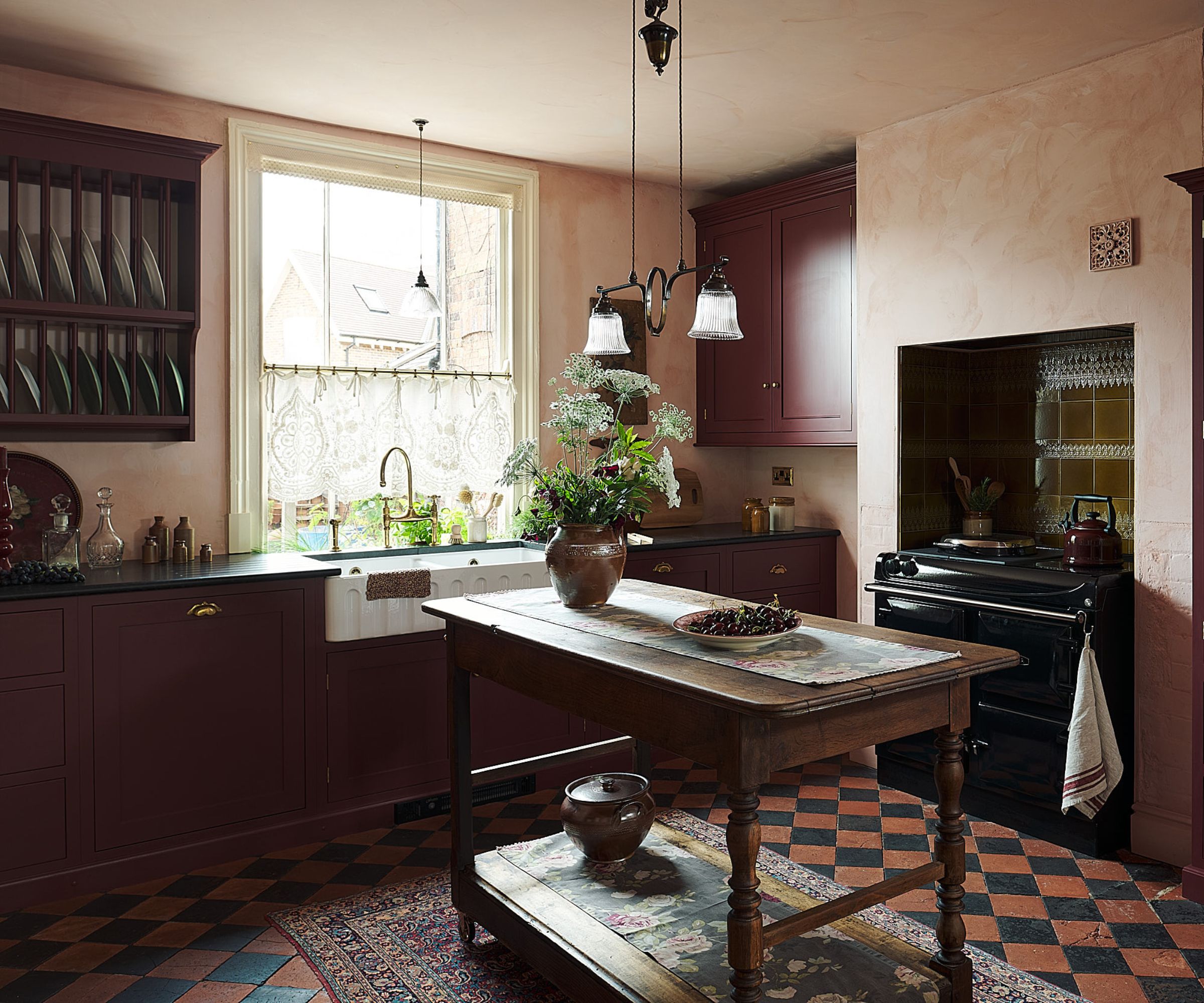 A burgundy kitchen with patterned floor tiles