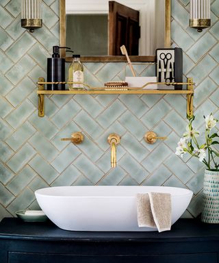 Wall mounted gold taps on green tiles
