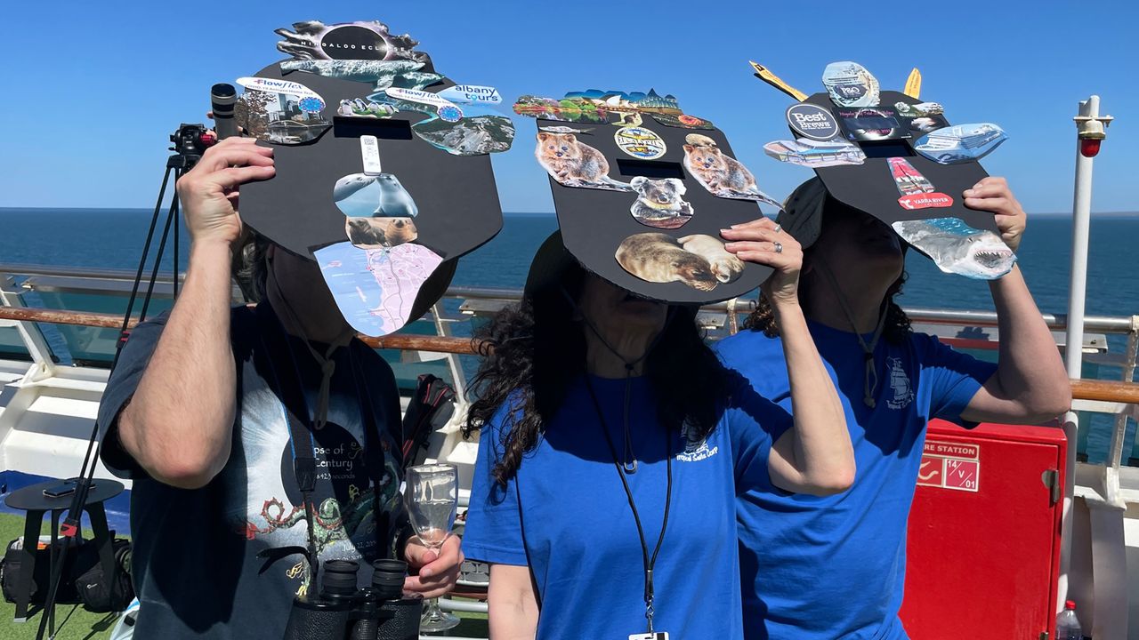 Onlookers use solar eclipse viewers to safely see the show before totality.