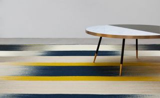 Gold and black coffee table on blue, yellow and white stripy floor